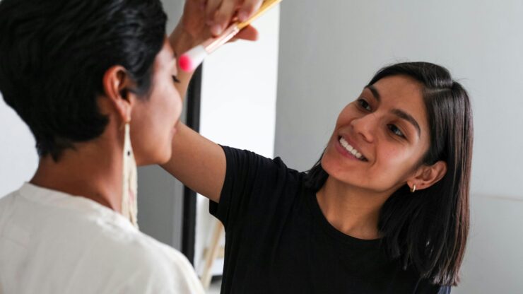 Makeup artist working on a client indoors, highlighting beauty and skill in artistry.